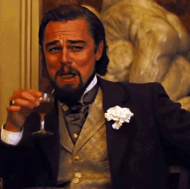 a man in a suit and tie is drinking from a glass