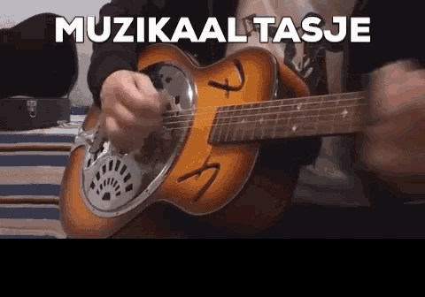 a man is playing an acoustic guitar with the words muzikaal tasje in the background
