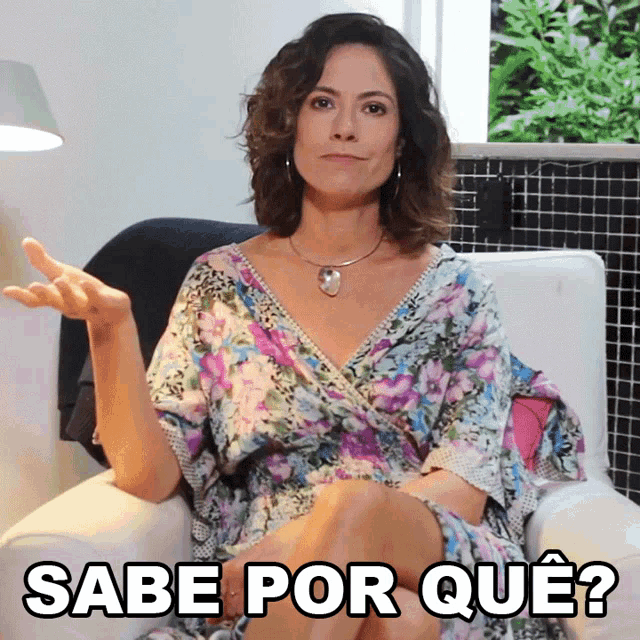 a woman in a floral dress is sitting in a chair with the words sabe por que written below her