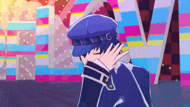 a man in a blue hat is covering his face with his hand in front of a colorful wall .