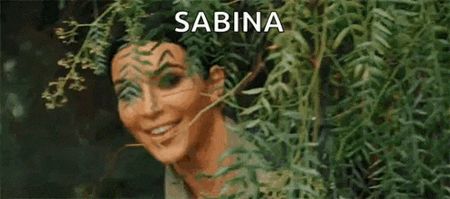 a woman is peeking out of a tree and smiling .
