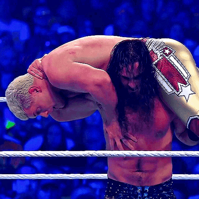 a wrestler is carrying another wrestler on his shoulders in a ring
