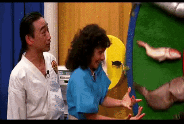 a man and a woman are standing next to each other in front of a green screen with fish on it