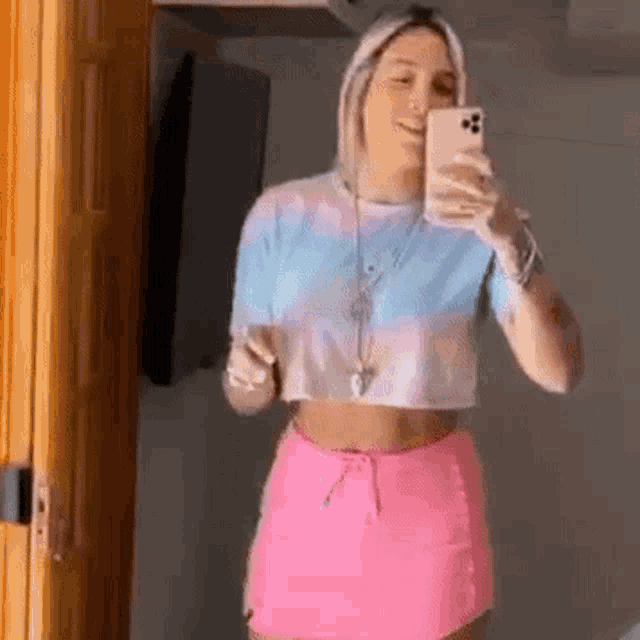 a woman is taking a selfie in front of a mirror with her phone .
