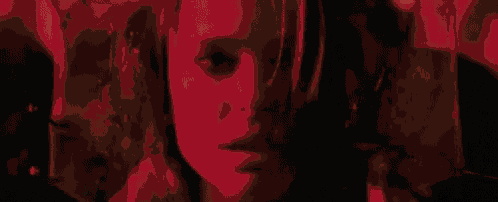 a close up of a woman 's face in a dark room with a red background .