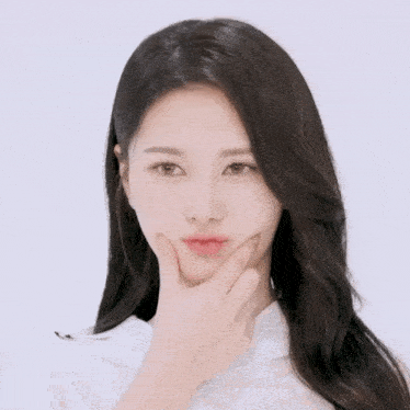 a woman with long hair is smiling and touching her face with her hand