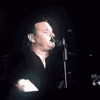 a man is singing into a microphone in a dark room