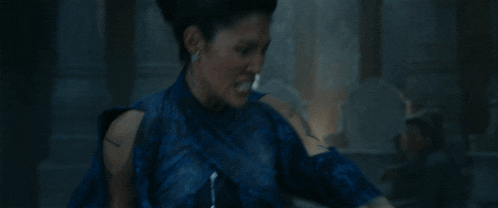 a woman in a blue dress is standing next to a man in a gray robe in a room .