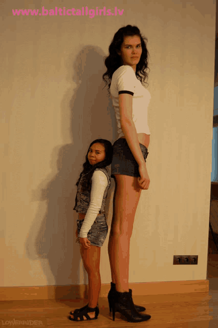 two women standing next to each other with the website www.baltictallgirls.lv in the upper right corner