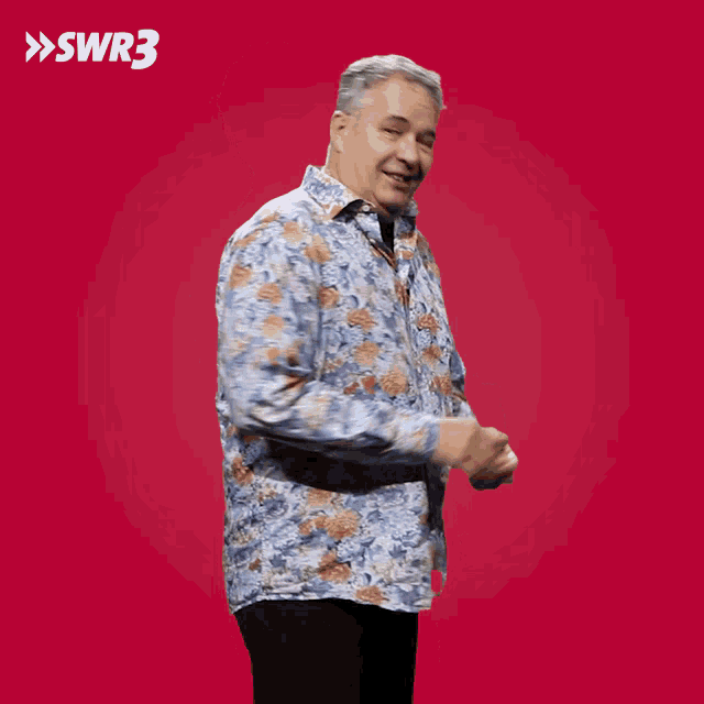 a man in a blue shirt is standing in front of a red background with swr3 written on it