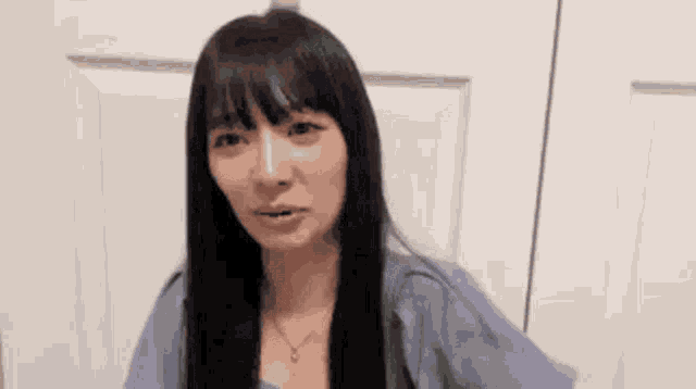 a woman with long black hair is standing in front of a white door and crying .