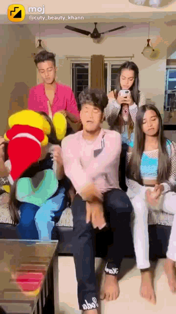 a group of young people are sitting on a couch with a stuffed animal in the middle
