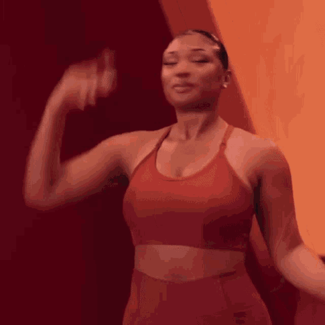 a woman in a red sports bra is standing in front of a red wall .