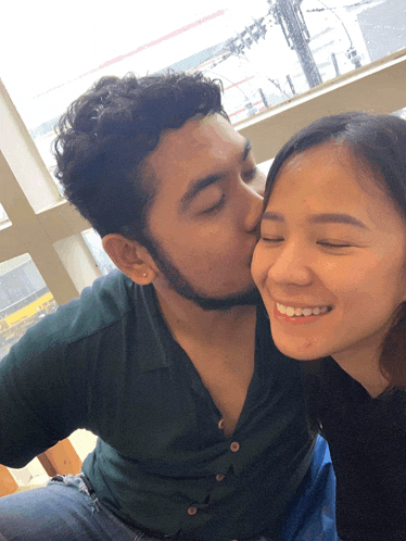 a man kisses a woman on the cheek and they both smile