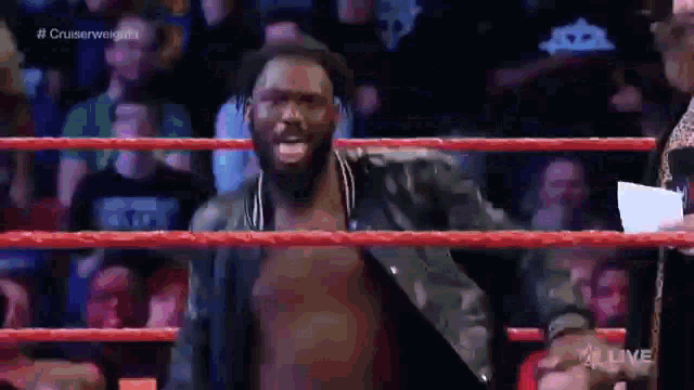 a man without a shirt is standing in a wrestling ring with a crowd watching .