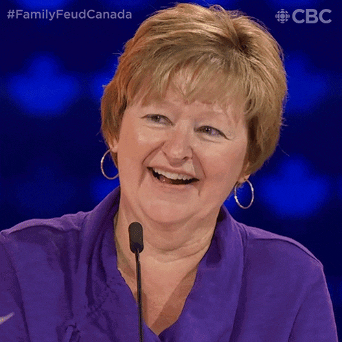a woman in a purple shirt is smiling in front of a microphone with the hashtag #familyfeudcanada