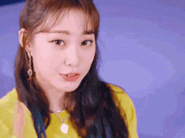 a close up of a woman wearing a yellow shirt and necklace .