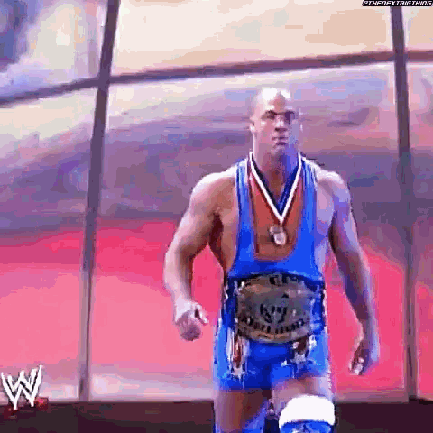 a wrestler wearing a medal around his neck is walking on a stage