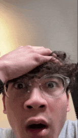 a man wearing glasses is making a surprised face .