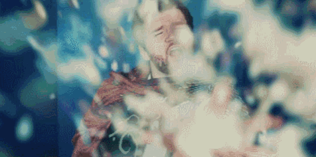 a man with a beard is floating in the water with bubbles coming out of his mouth .