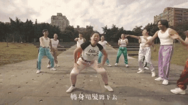 a group of people are dancing in a park and one of them is wearing a shirt that says cute