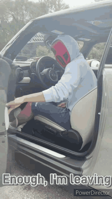 a man in a hoodie is sitting in the driver 's seat of a car with the caption enough im leaving