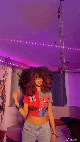a woman with red hair is standing in a room with purple lights and a spider-man shirt on .