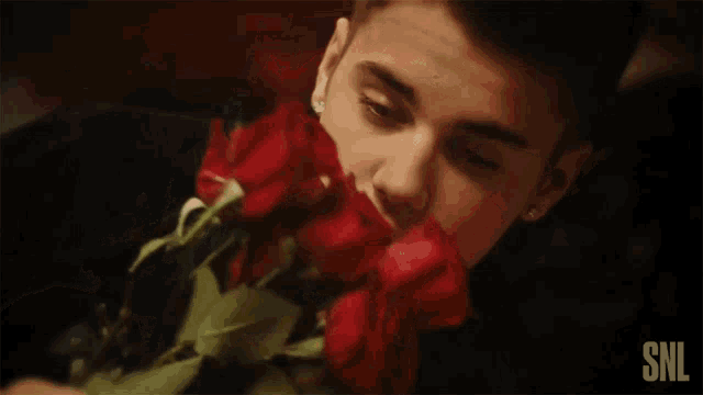 a person holding a bunch of red roses with snl written on the bottom right