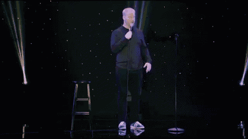 a man in a black shirt is holding a microphone in front of his face .
