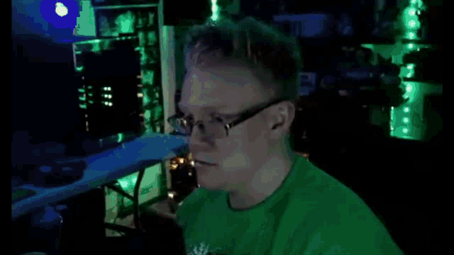 a man in a green shirt is sitting in front of a computer monitor