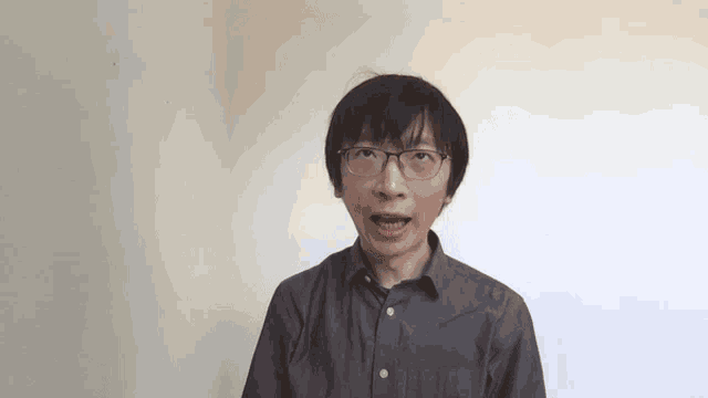 a man wearing glasses and a grey shirt is looking at the camera