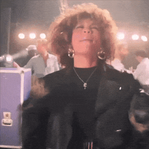 a woman wearing a necklace with a cross on it is dancing