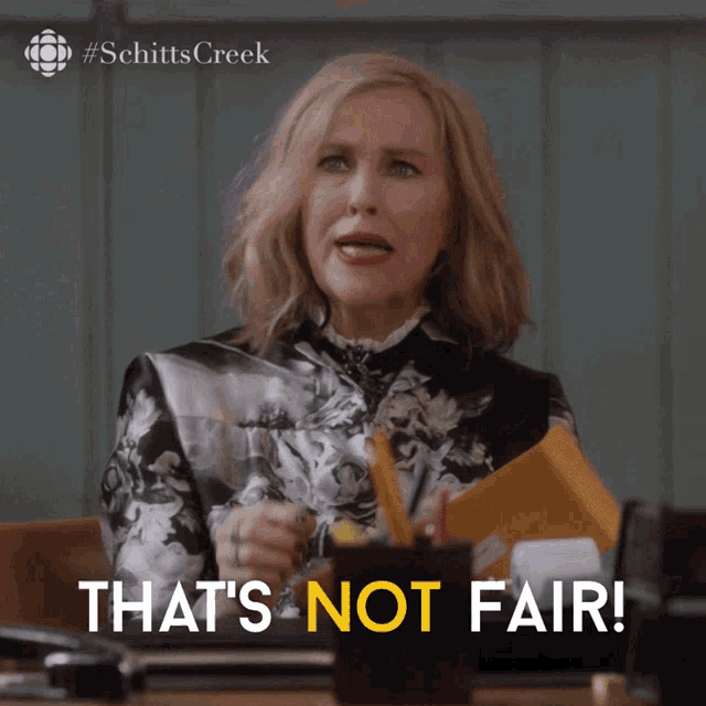 a woman is sitting at a desk with the words that 's not fair