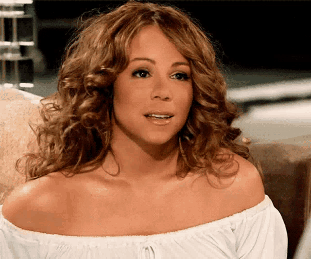a woman with curly hair wearing a white off the shoulder shirt