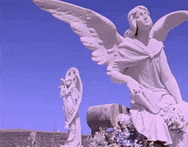 a statue of a woman with wings sitting on a grave