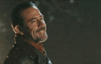 a man with a beard is smiling and wearing a leather jacket and scarf .