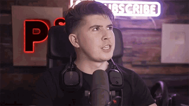a man wearing headphones stands in front of a microphone in front of a sign that says subscribe