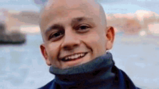 a close up of a bald man wearing a turtleneck sweater and smiling .