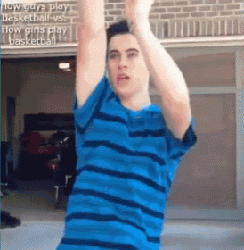 a man in a blue striped shirt is standing in front of a garage door with his arms in the air