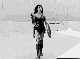 a black and white photo of a woman in a wonder woman costume holding a shield and a lasso .
