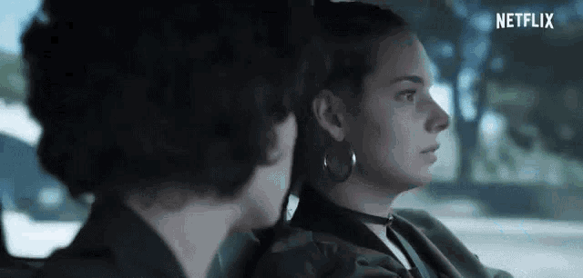 a man and a woman are sitting in a car and talking to each other .