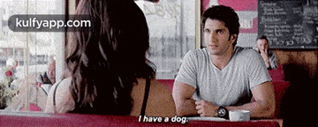 a man and a woman are sitting at a table and the woman says i have a dog