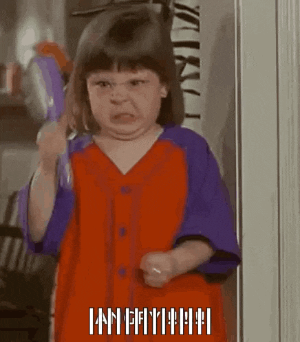 a little girl in a red and purple shirt is holding a toothbrush and making a funny face .