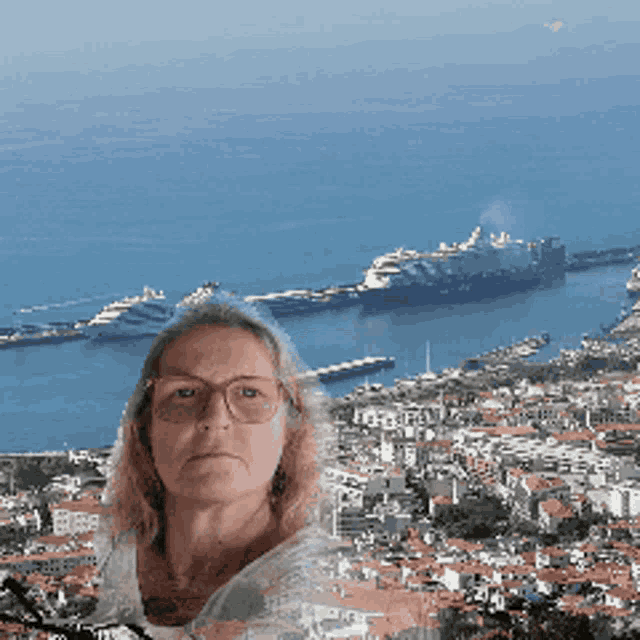 a woman wearing glasses stands in front of a large body of water and a city