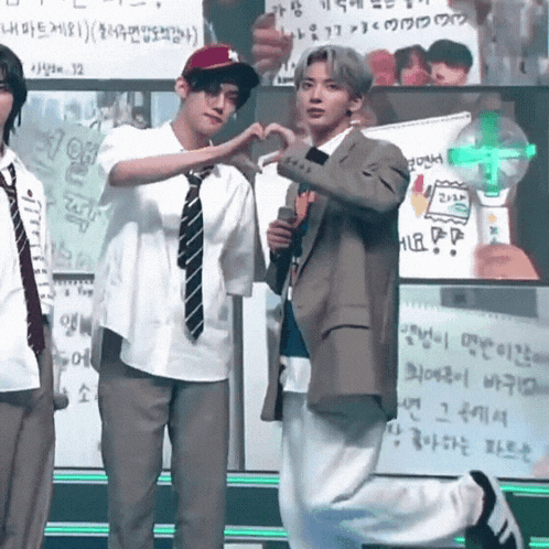 a man in a suit is making a heart with his hands
