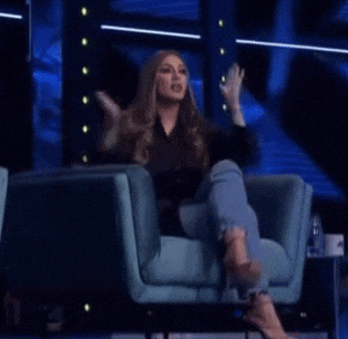 a woman is sitting in a chair with her legs crossed and talking