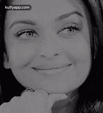 a close up of a woman 's face with a ring on her finger .