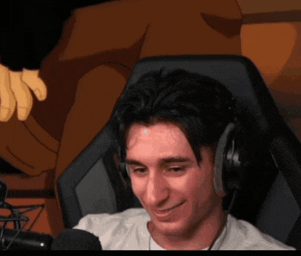 a man wearing headphones sits in front of a microphone and smiles