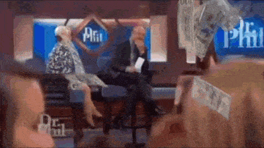 a man and woman are sitting on a stage with money falling from the ceiling .