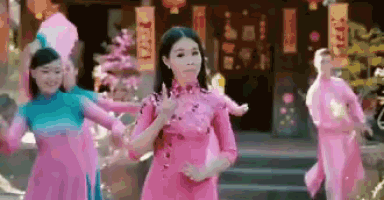a woman in a pink dress is dancing in front of a group of women in pink dresses .
